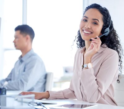 Shot of a young call centre agent sitting with her colleague and using her computer.